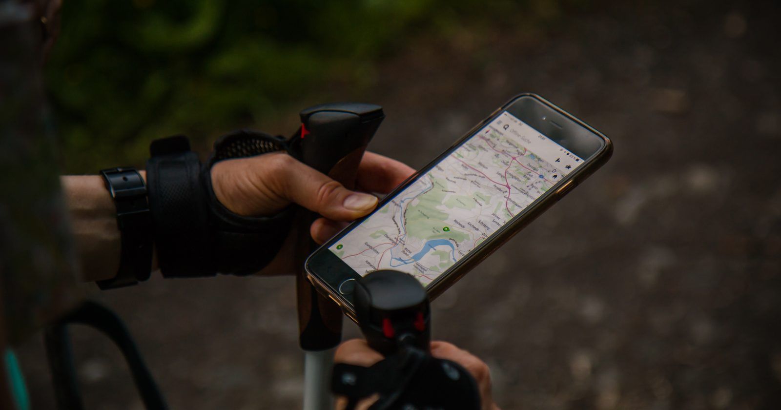Mão segurando um celular com um mapa na tela, como quem procura uma empresa no Google Maps
