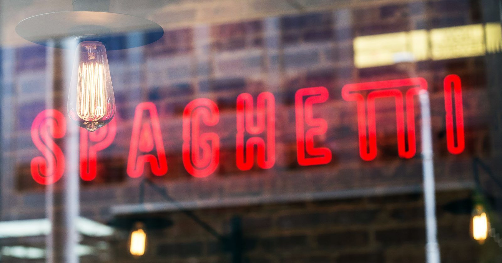 Local restaurant with a red neon Spaghetti sign in the window, the kind of business a Google Business Profile helps customers find