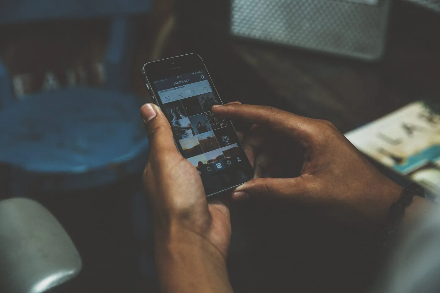Person holding a smartphone with a photo grid on the screen, as a customer does when checking a business and its Google reviews