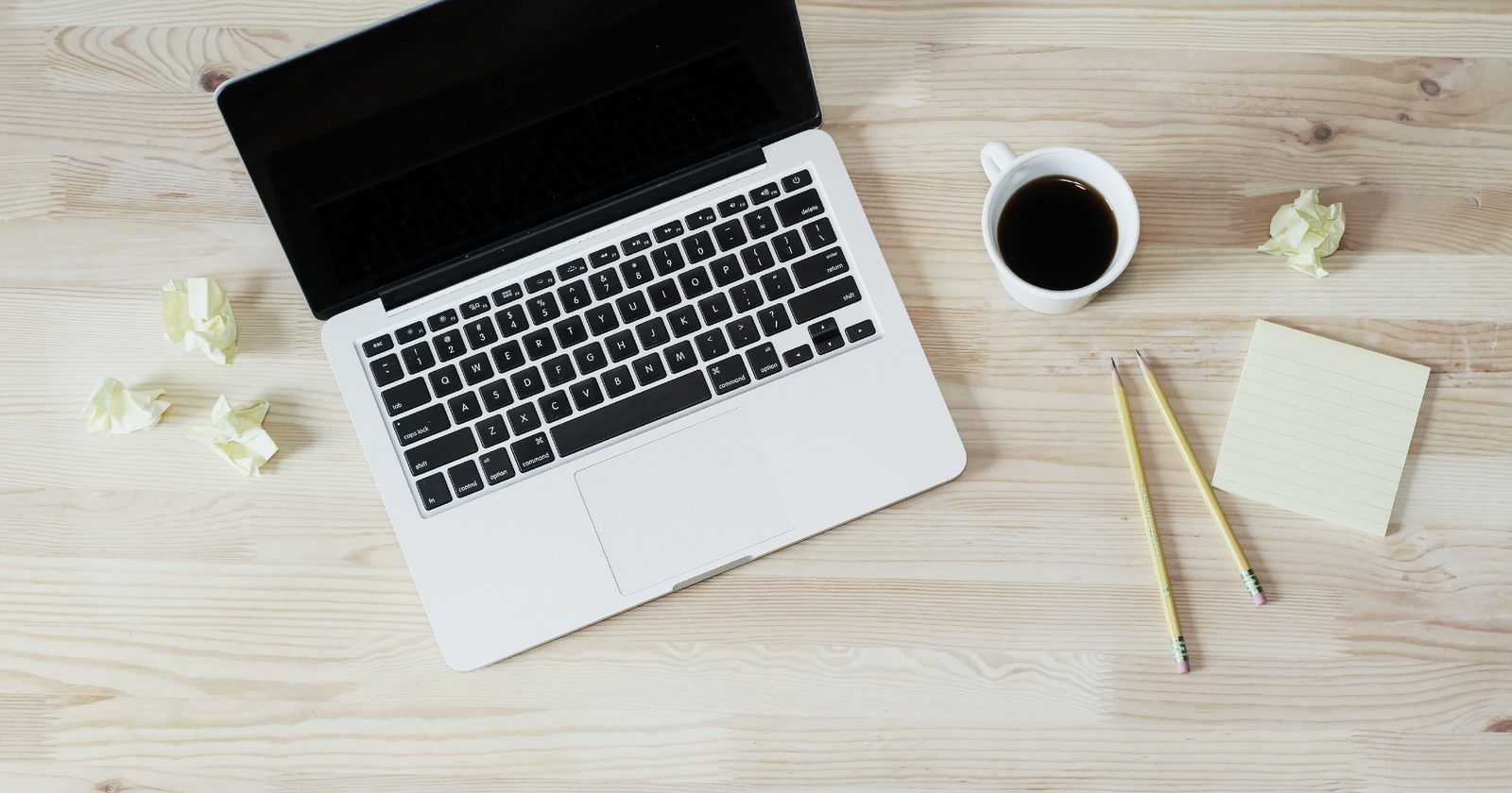 Notebook, café, lápis e anotações sobre uma mesa, como quem calcula quanto custa um site profissional